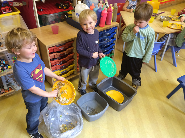 Helping to clear the lunch plates at Acorns Nursery School, Cirencester.