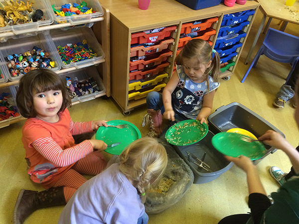 Helping to clear the plates ready for washing up at Acorns Nursery School, Cirencester.