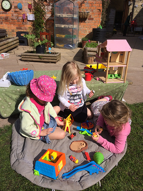 Playing on the grass in the garden at Acorns Nursery School, Cirencester.