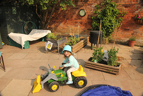 Gardening with the (toy) tractor at Acorns Nursery School, Cirencester.